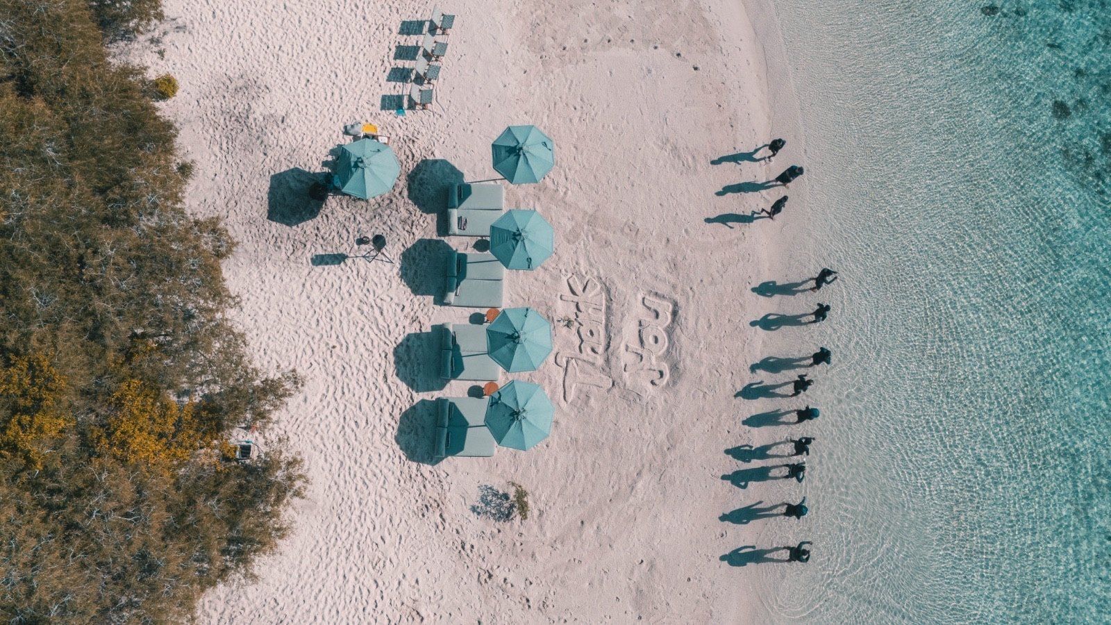 Aerial view of a beach dinner set up on white sand